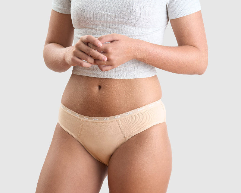 Girl standing in studio wearing grey top and Neutral coloured Eltee Sydney Bumpers Briefs period underwear