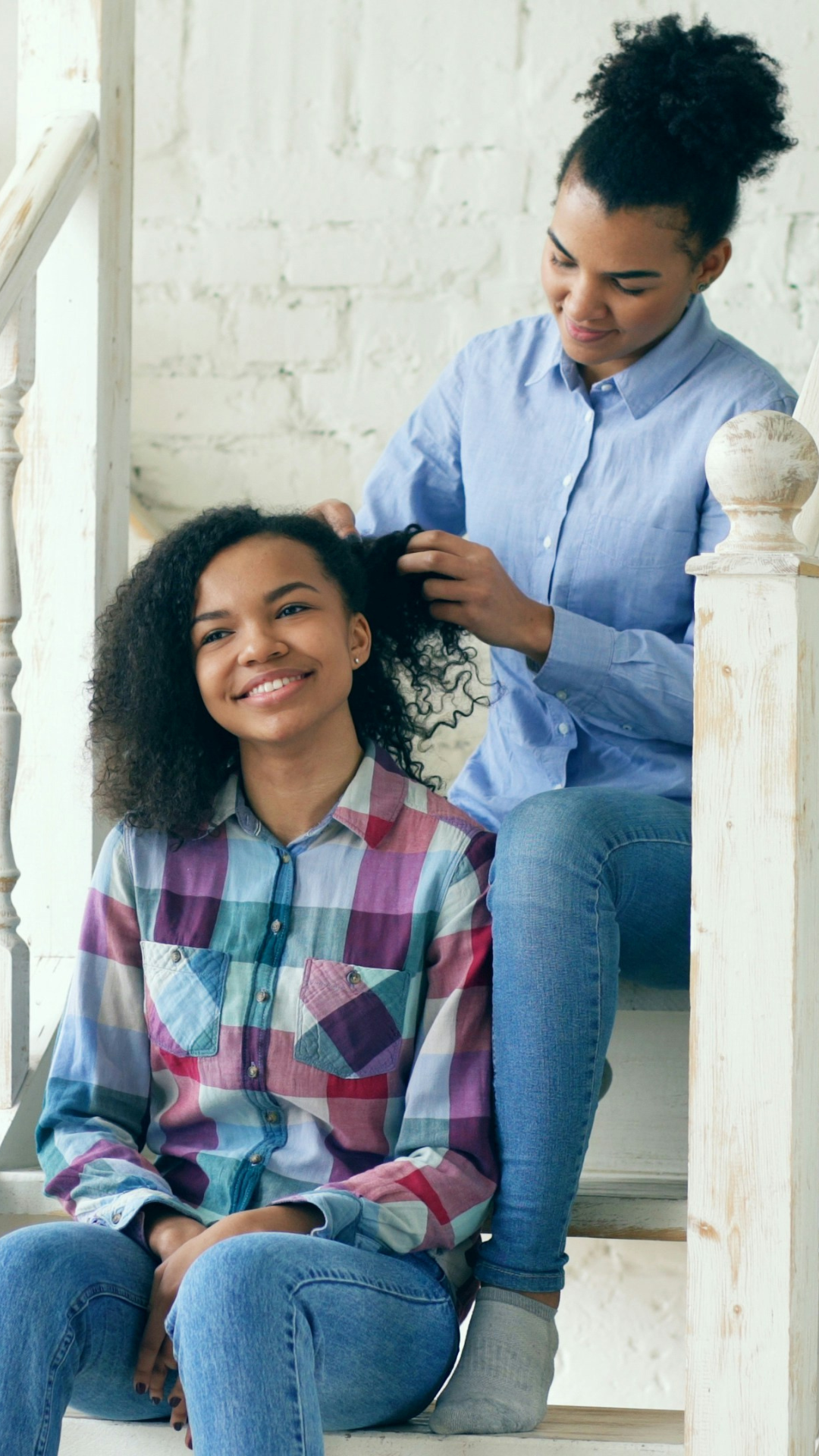 Mother sitting behind girl doing her hair